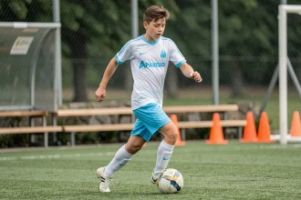 Jeune joueur de l'académie de l'Olympique de Marseille en train de dribbler lors d'un entraînement au centre de formation
